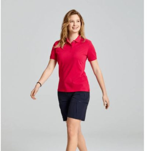 Woman wearing a red polo shirt and navy shorts on a gray background