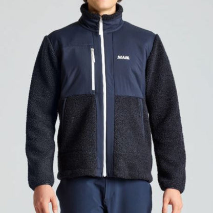 Person wearing a black and navy fleece jacket with a visible brand logo on a gray background