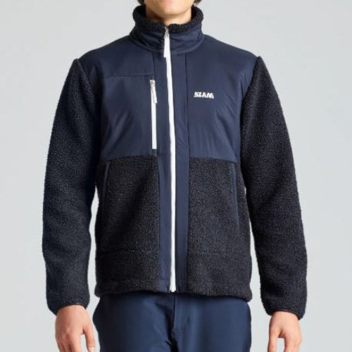Person wearing a black and navy fleece jacket with a visible brand logo on a gray background
